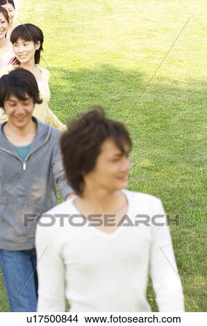 Friends walking in single file on a field View Large Photo Image Picture - Friends walking in single file on a field. Fotosearch