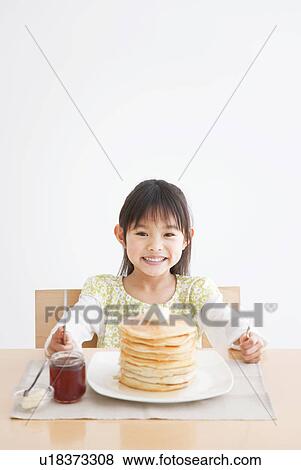 Stock Photo - Girl about to enjoy a stack of pancakes. Fotosearch