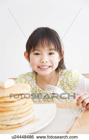 Stock Photograph - Girl about to enjoy a stack of pancakes. Fotosearch