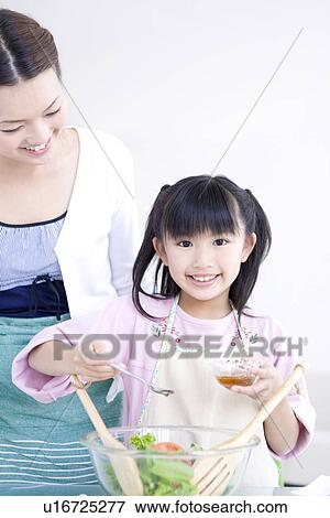 Stock Photo - Girl adding salad dressing to salad with her mother. Fotosearch
