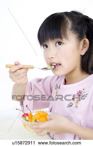 Stock Image - Girl eating fruit salad. Fotosearch