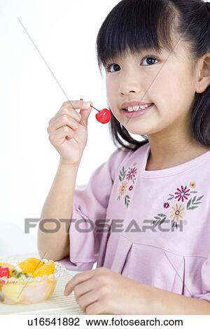 Stock Image - Girl eating fruit salad. Fotosearch