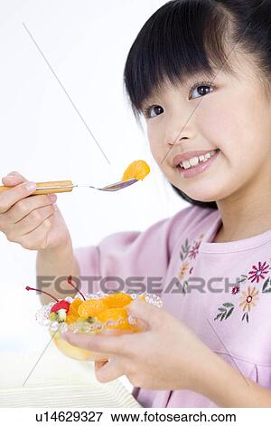 Stock Photo - Girl eating fruit salad. Fotosearch