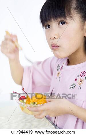 Stock Photo - Girl eating fruit salad. Fotosearch