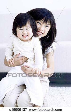 Stock Photo - Girl holding her baby sister. Fotosearch