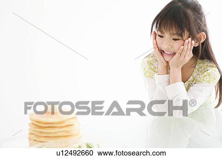 Stock Image - Girl looking at food on the table. Fotosearch