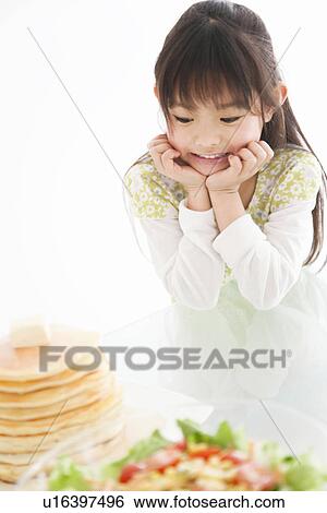 Stock Photograph - Girl looking at food on the table. Fotosearch