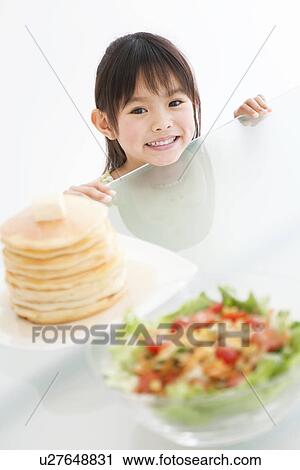 Stock Image - Girl peeking over the table at food. Fotosearch
