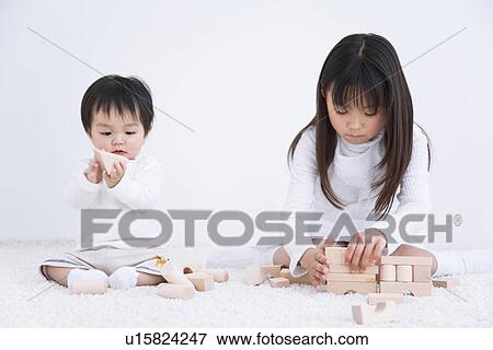 Girl playing with blocks on a rug next to her baby brother View Large Photo Image Stock Photo - Girl playing with blocks on a rug next to her baby brother. Fotosearch