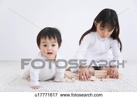 Girl playing with blocks on a rug next to her baby brother View Large Photo Image Stock Photo - Girl playing with blocks on a rug next to her baby brother. Fotosearch