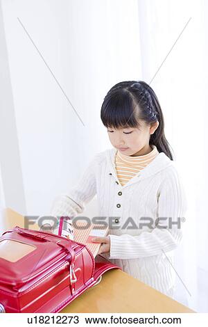 Stock Image - Girl taking her books out of her backpack. Fotosearch