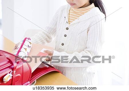 Stock Photography - Girl taking her books out of her backpack. Fotosearch