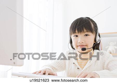 Stock Image - Girl wearing a headset and using a computer. Fotosearch