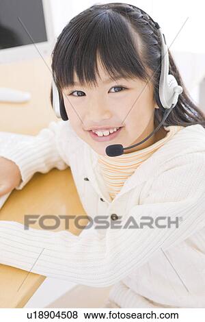 Girl wearing a headset and using a computer View Large Photo Image Stock Photo - Girl wearing a headset and using a computer. Fotosearch