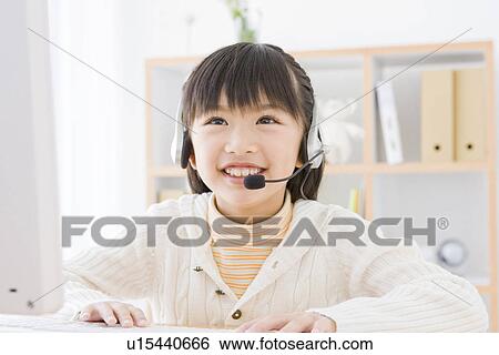 Girl wearing a headset and using a computer View Large Photo Image Stock Photograph - Girl wearing a headset and using a computer. Fotosearch