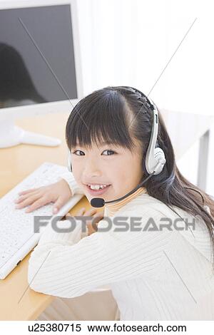 Stock Photography - Girl wearing a headset and using a computer. Fotosearch