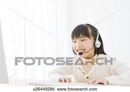 Stock Photography - Girl wearing a headset and using a computer. Fotosearch