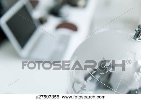 Stock Photograph - Glass globe on desk in office. Fotosearch