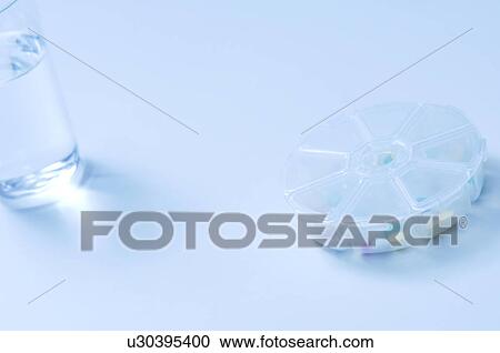 Stock Image - Glass of water and pill case. Fotosearch