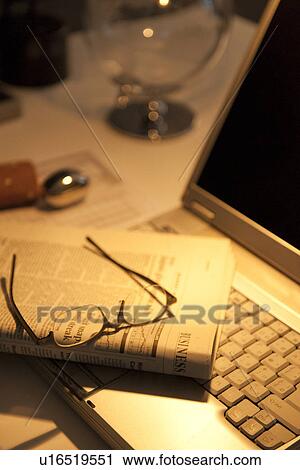 Stock Image - Glasses resting on newspaper in office. Fotosearch