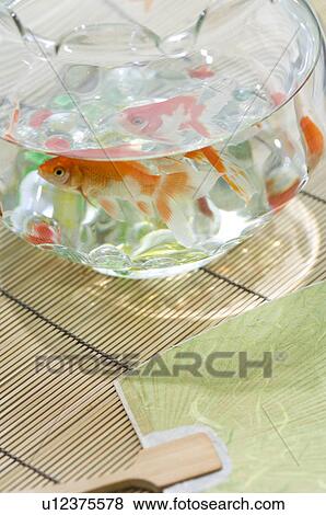 Stock Photo - Goldfish in a fishbowl on a tatami mat next to a fan. Fotosearch