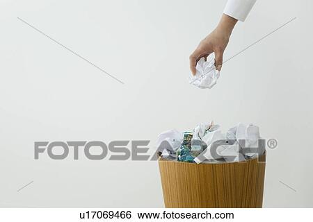 Stock Photograph - Hand dropping crumpled paper into wastepaper bin. Fotosearch