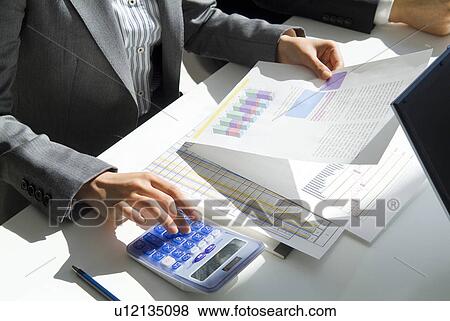 Stock Photo - Hand of the businesswoman using a calculator. Fotosearch