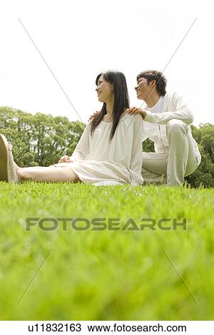 Happy young couple sitting together outside View Large Photo Image Stock Image - Happy young couple sitting together outside. Fotosearch