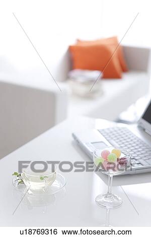 Herbal tea, a glass of candy and a laptop on a table View Large Photo Image Stock Photograph - Herbal tea, a glass of candy and a laptop on a table. Fotosearch