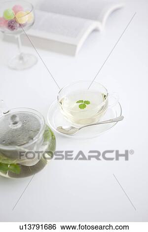 Herbal tea, a glass of candy and an open book View Large Photo Image Stock Photograph - Herbal tea, a glass of candy and an open book. Fotosearch
