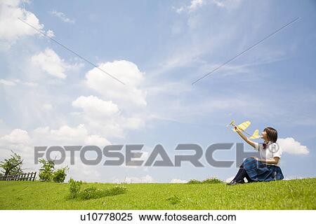 High school girl sitting in field throwing paper airplane View Large Photo Image Stock Photography - High school girl sitting in field throwing paper airplane. Fotosearch
