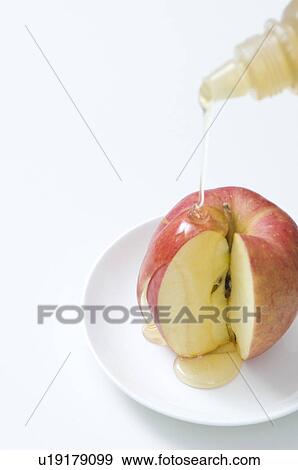 Stock Photo - Honey being poured onto an apple. Fotosearch