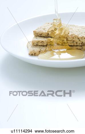 Picture - Honey being poured onto crackers. Fotosearch