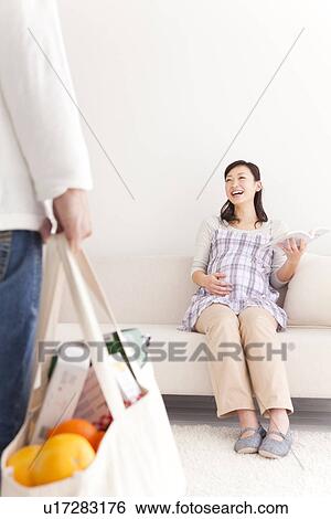 Stock Photograph - Husband arriving home to his pregnant wife with the groceries. Fotosearch