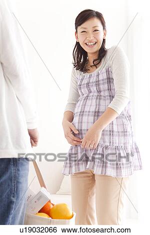Stock Photograph - Husband arriving home to his pregnant wife with the groceries. Fotosearch
