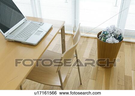 Stock Photograph - Laptop computer on desk near wastepaper bin. Fotosearch