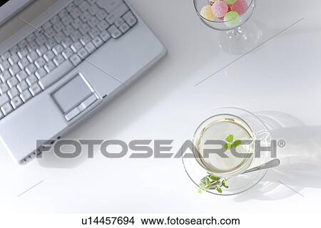 Picture - Laptop, herbal tea and a glass of candy. Fotosearch