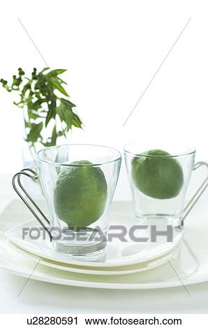 Stock Image - Limes inside two glass tea cups. Fotosearch