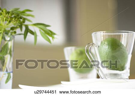 Stock Image - Limes inside two glass tea cups. Fotosearch