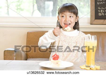 Stock Image - Little girl eating strawberry cake. Fotosearch