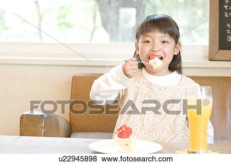 Stock Photo - Little girl eating strawberry cake. Fotosearch
