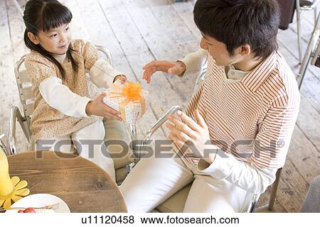 Little girl giving father a present at cafe View Large Photo Image Stock Photo - Little girl giving father a present at cafe. Fotosearch