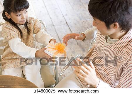 Little girl giving father a present at cafe View Large Photo Image Stock Photography - Little girl giving father a present at cafe. Fotosearch