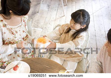 Little girl giving mother a present at a cafe View Large Photo Image Stock Image - Little girl giving mother a present at a cafe. Fotosearch