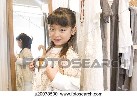 Little girl holding up dress in front of shop mirror View Large Photo Image Stock Image - Little girl holding up dress in front of shop mirror. Fotosearch