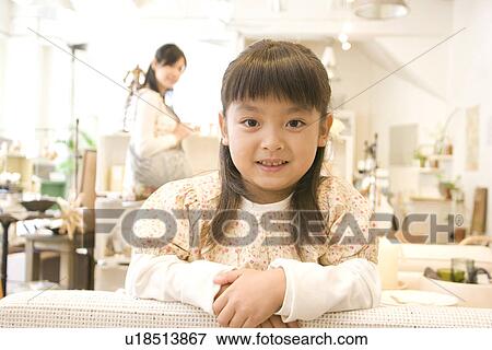 Little girl leaning over back of sofa in a furniture store with her mother shopping in the background View Large Photo Image Stock Photo - Little girl leaning over back of sofa in a furniture store with her mother shopping in the background. Fotosearch