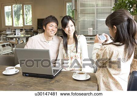 Stock Image - Little girl looking at a photo she has taken of her parents on a digital camera. Fotosearch
