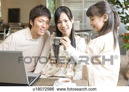 Stock Photograph - Little girl showing parents a photo she has taken of them on a digital camera. Fotosearch