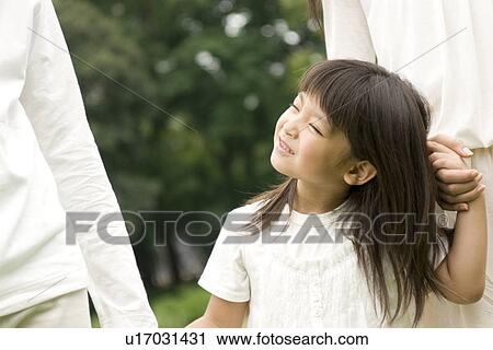 Stock Image - Little girl walking with her parents hand in hand. Fotosearch