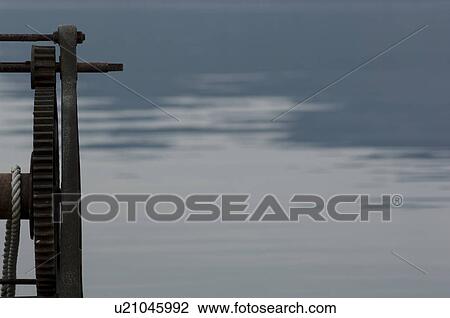 Stock Image - Machine with gears beside water. Fotosearch